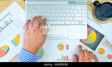 Businessman accountant working at desk with graphs and modern touch screen computer, overhead. Stock Photo