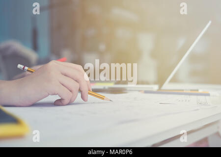 Architect or planner working on drawings for construction plans at a table Stock Photo