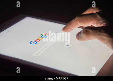 BANGKOK, THAILAND - FEBRUARY 14, 2017: A man's hand is touching screen on tablet at night for searching on Google search engine. Google is the most po Stock Photo