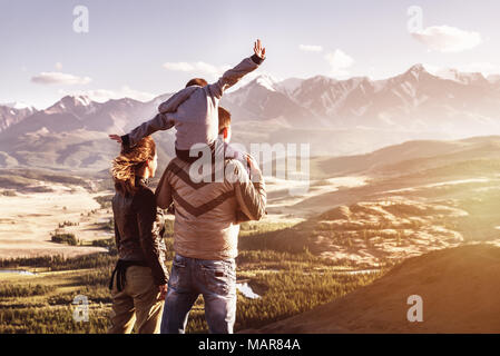 Happy family with little son stands against mountains sunset. Travel tourism adventures concept Stock Photo