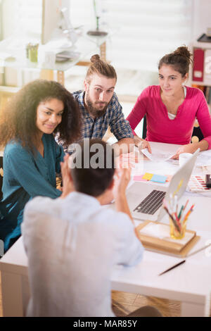Young colleagues share ideas in front of a laptop.New project Stock Photo