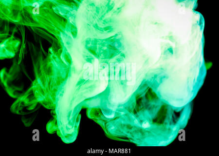 Dense green multicolored smoke on a black isolated background. Background of smoke vape Stock Photo