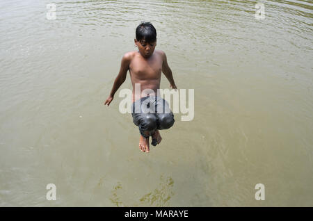 Agartala, India. 28th Mar, 2018. Indian boys jump into a Lake to beat ...