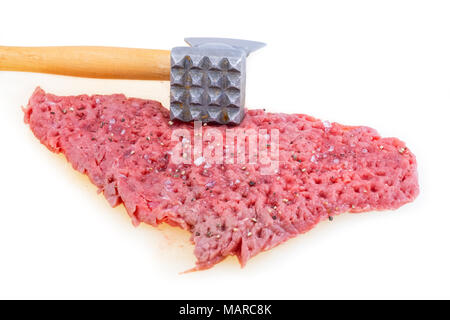 Hands tenderizing meat with kitchen hammer on a white board Stock Photo