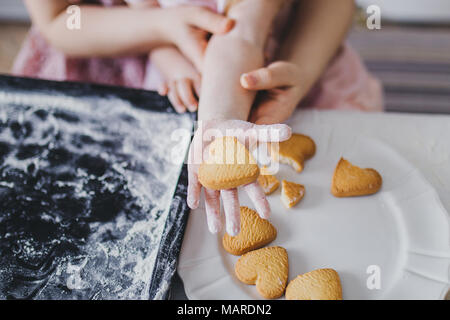 Mom and daughter lay out cookies on a white plate Stock Photo