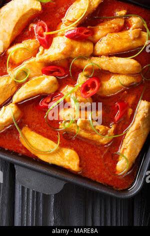 Delicious spicy chicken panang curry close-up on a black plate on the table. Vertical top view from above Stock Photo