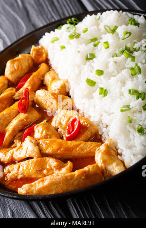 Thai chicken panang curry with rice and green onion close-up on a plate. vertical Stock Photo