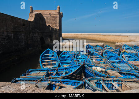 Blue fishing boats in Essaouira old harbor below Portuguese fortress Sqala du Port, Morocco Stock Photo