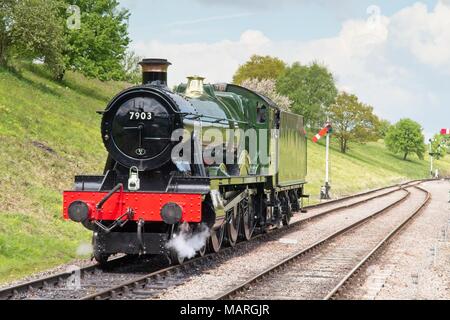 A view of the green steam engine Foremarke Hall, a modified Hall Class engine 7903 on the railway track infant of a grass bank with signals behind. Stock Photo