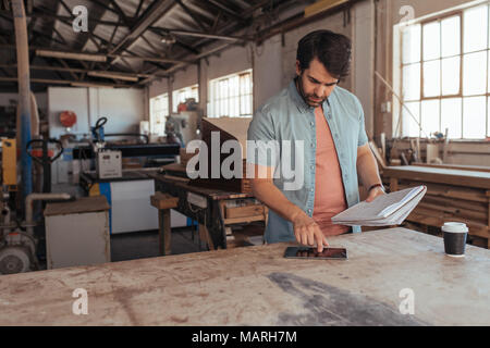 Young woodworker coming up with new designs in his workshop Stock Photo