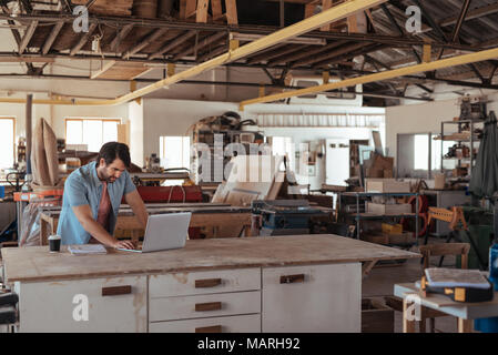 Young woodworker working online at a bench in his workshop Stock Photo