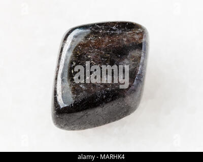 macro shooting of natural mineral rock specimen - tumbled anthophyllite gemstone on white marble background from Tirol, Austria Stock Photo