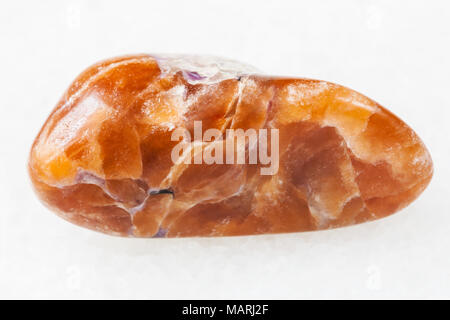 macro shooting of natural mineral rock specimen - polished tinaksite gemstone on white marble background from Murun Massif, Yakutia, Russia Stock Photo