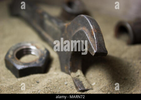 Old wrench and nuts on the sand Stock Photo