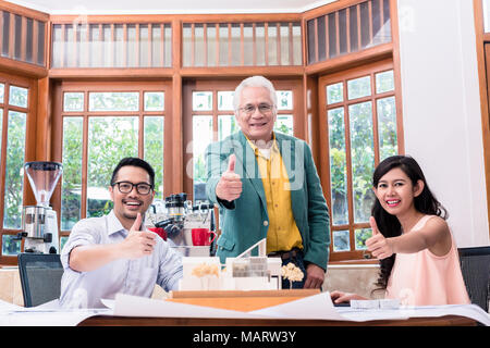 Team of three successful architects showing thumbs up Stock Photo