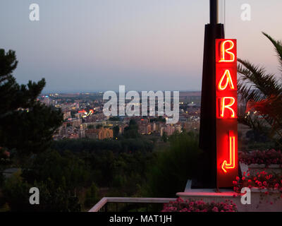 Neon lit BAR sign with arrow. Bulgaria town in the background Stock Photo