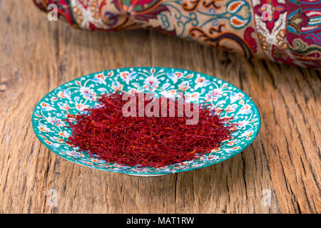 Red Threads And Yellow Style High Grade And Strength Of Dry Saffron Spice On Persian Turquoise Handmade Design Plate On Wooden Table Stock Photo