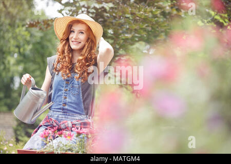 Beautiful woman in yellow sunhat relaxing in the backyard on a sunny summer day after gardening Stock Photo