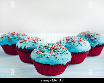 Festive, fragrant cupcakes, covered with turquoise glaze and bright decoration for baking on a white background Stock Photo