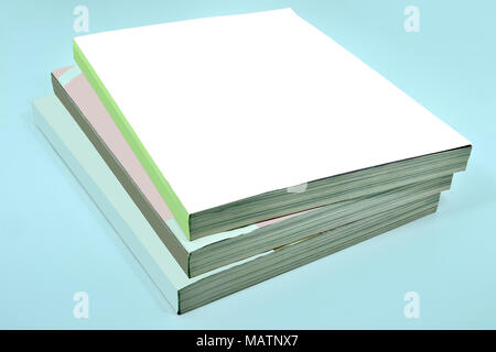 Stack of three thick magazines or books, catalogs with a blank white soft cover on a blue background - a mock up for demonstrating your design Stock Photo
