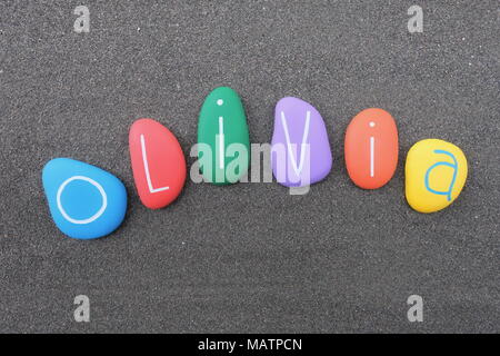 Olivia, feminine given name with multicolored painted stones over black volcanic sand Stock Photo