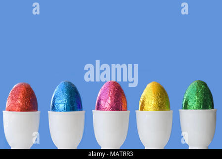 A line of colourful eggs.  Space for copy on vivid blue background Stock Photo