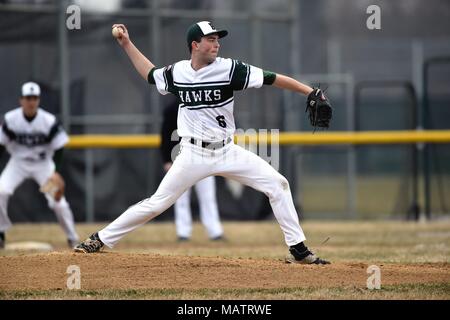 Pitcher delivering a pitch to an opposing hitter during a high school baseball game. USA. Stock Photo