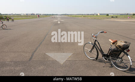 An upright Dutch style bike is positioned on the runway of the now abandoned Tempelhof Feld Airport in Berlin, Germany, which is now used as a park Stock Photo