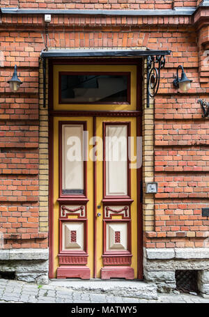 Red wooden door with glass in a red brick building in Europe. Architectural theme Stock Photo