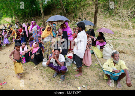 Rohingya people take rest beside a road after crossing the Bangladesh-Myanmar border, at Ukhiya, Bangladesh. Stock Photo