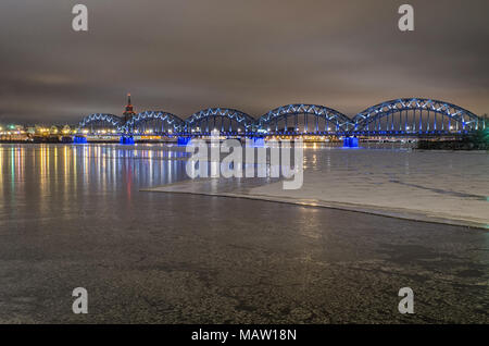 railway bridge over the frozen river Daugava in Riga, Latvia, on a winter evening Stock Photo