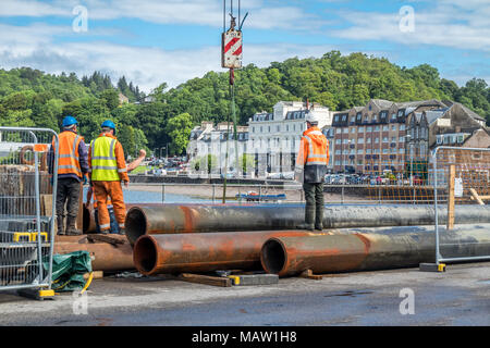 Construction site workers moving huge pipes in the harbour Stock Photo