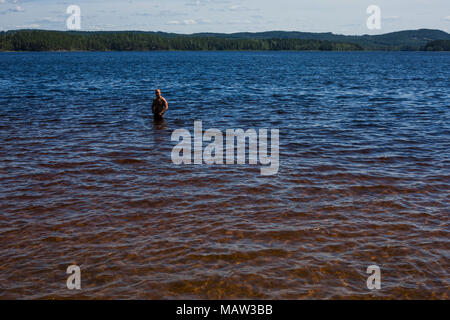 A man wading in a lake near Kopparberg, Sweden. Stock Photo