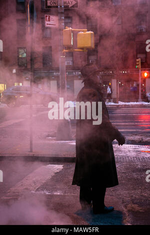 A man wearing a fedora standing on a steamy street in New York city. Stock Photo