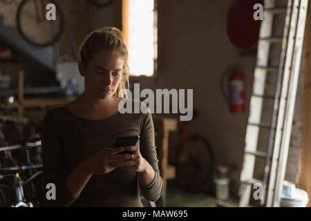 Female mechanic using mobile phone in workshop Stock Photo