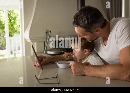 Father and son having breakfast while using digital tablet Stock Photo