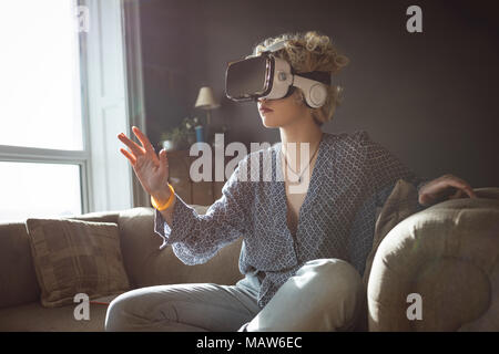 Woman using virtual reality headset in living room Stock Photo