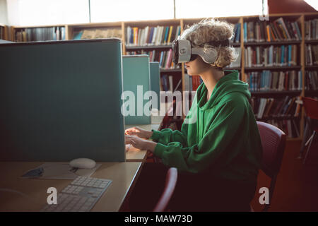 Woman using virtual reality headset with computer in library Stock Photo