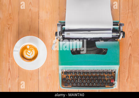 Old typewriter with a cup of coffee on wood table Stock Photo