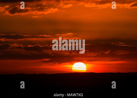 Dramatic sunset through clouds over the Menai Straits on the North Wales coast, as viewed from Caernarfon Stock Photo
