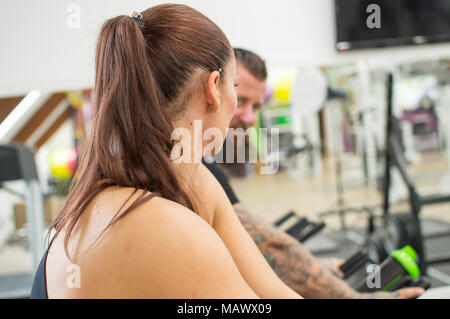 Thoughtful woman in a gym beside a tattooed man Stock Photo