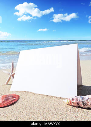 Blank white card or greeting card on the beach with copy space.  Summer holiday or beach vacation scene with shells and starfish. Holiday greetings. Stock Photo
