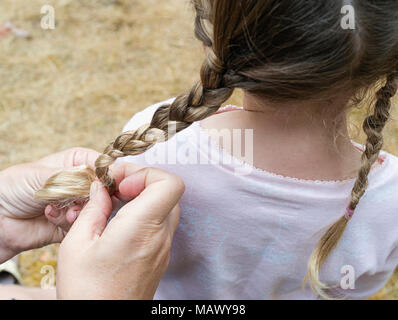 A woman braiding a young girls hair. Stock Photo