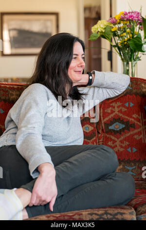 Woman seated casually on living room sofa Stock Photo