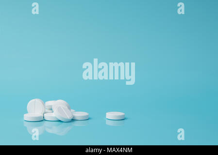 White pills lie on a blue surface Stock Photo