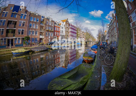 AMSTERDAM, NETHERLANDS, MARCH, 10 2018: Beautiful outdoor view of houses and Boats on Amsterdam Canal with frozen river, morning photo of colored hous Stock Photo