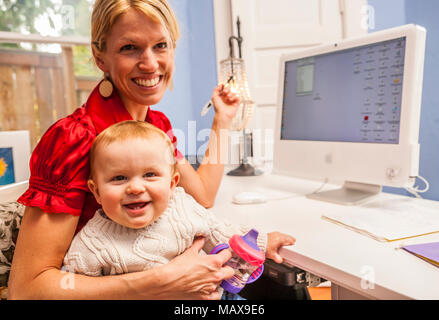 A portrait of a professional woman in her home office with her baby on her lap. Stock Photo