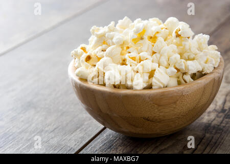 Popcorn in bowl on wooden table.