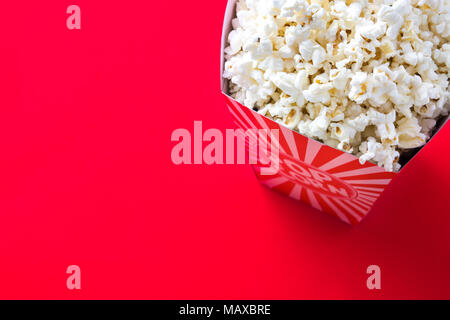 Striped box with popcorn on red background. Copyspace Stock Photo
