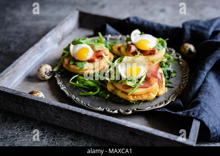 Savoury yoghurt and scallion pancakes with Black Forrest ham, smoked cheese slices, quail egg and arugula Stock Photo